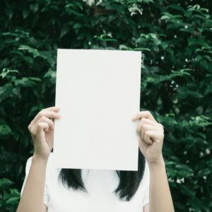 pexels-photo-388898-388898 A person holding a blank piece of paper in front of a lush leafy background.